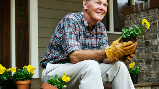 Man sitting on steps holding flowers that need to be planted